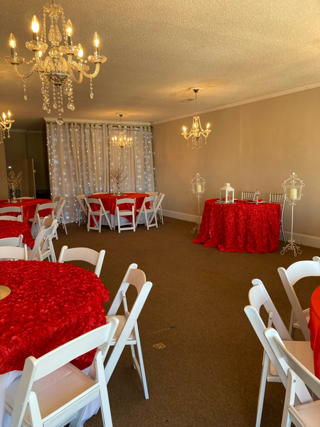 A room with red tables and chairs and a chandelier