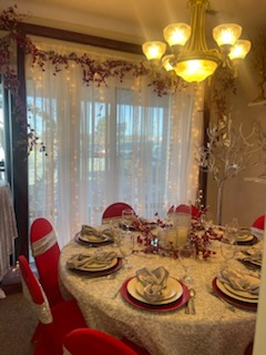 A dining room table with plates , utensils , and a chandelier.