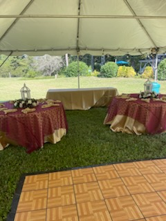 A tent with tables and a dance floor underneath it.