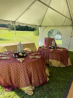 A couple of tables under a tent in the grass.