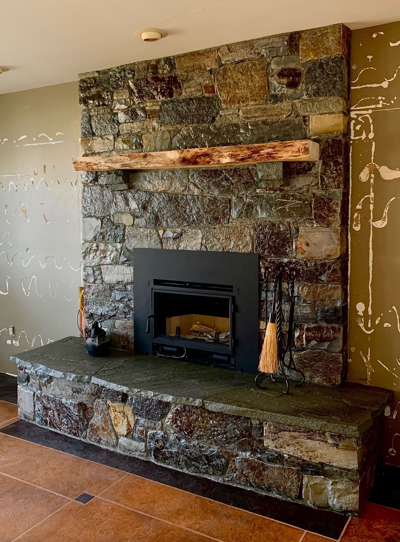 Stone fireplace with black firebox and wooden mantel.