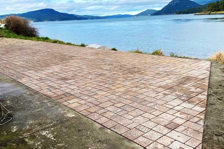 Brick patio overlooking a body of water with mountains in the background.