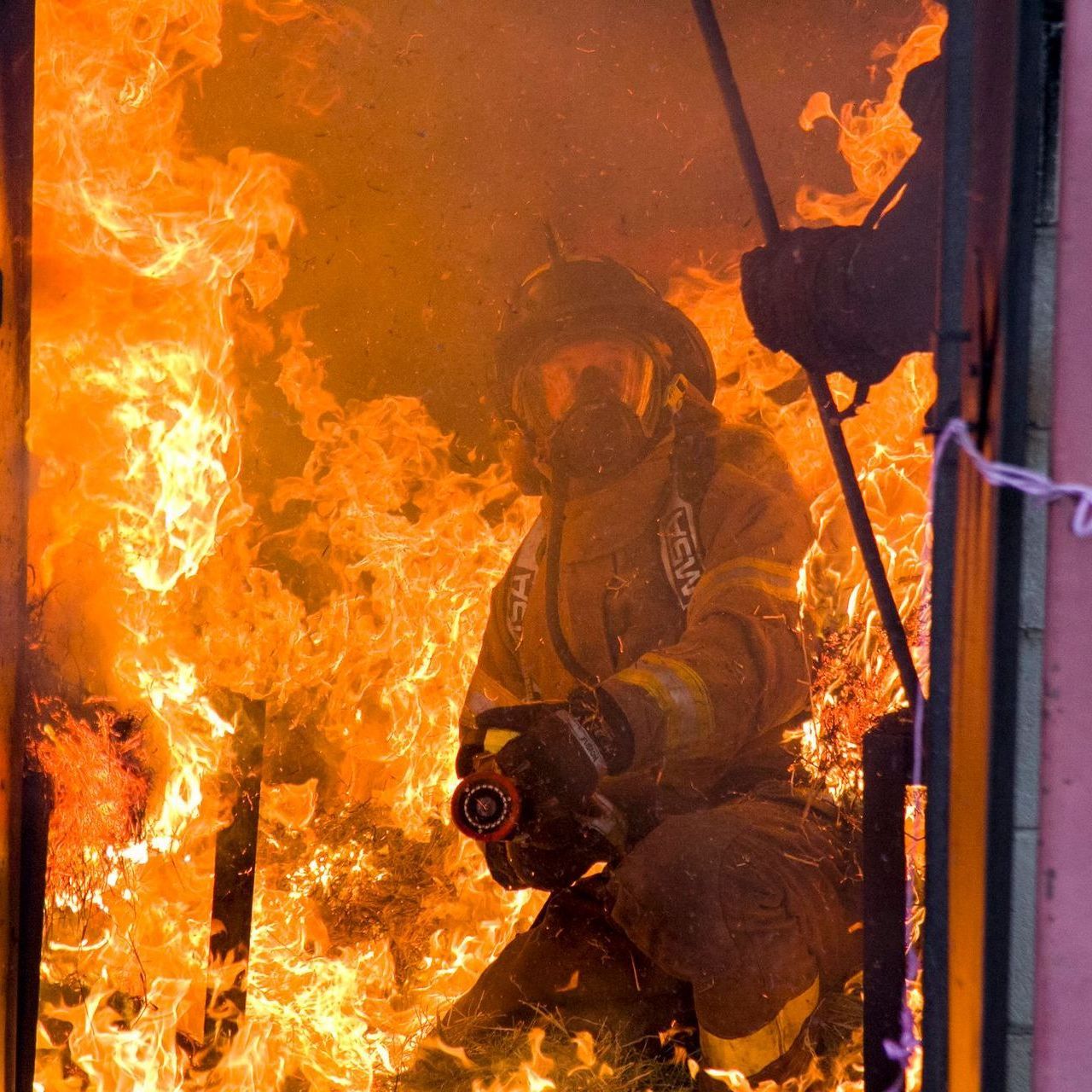 A fireman is kneeling in front of a large fire