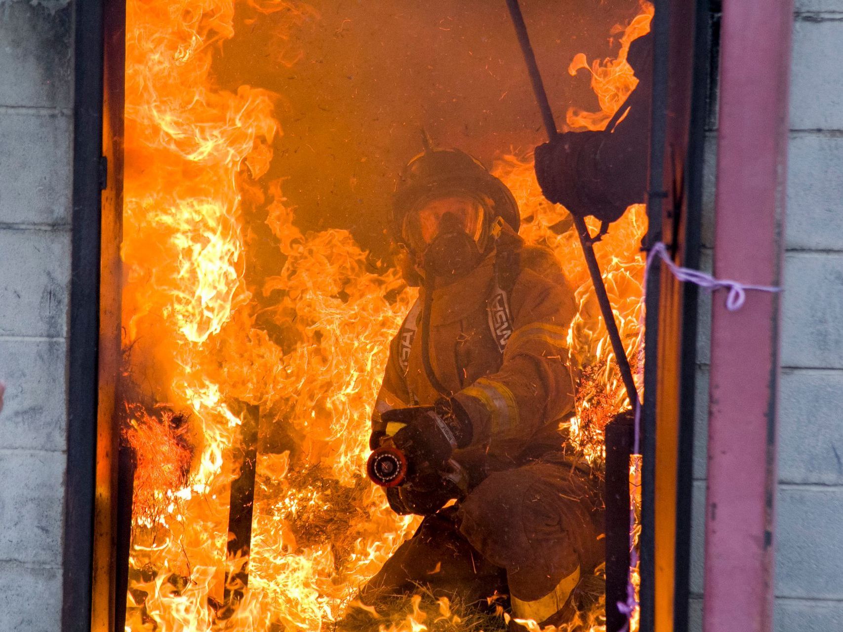 A fireman is standing in front of a large fire