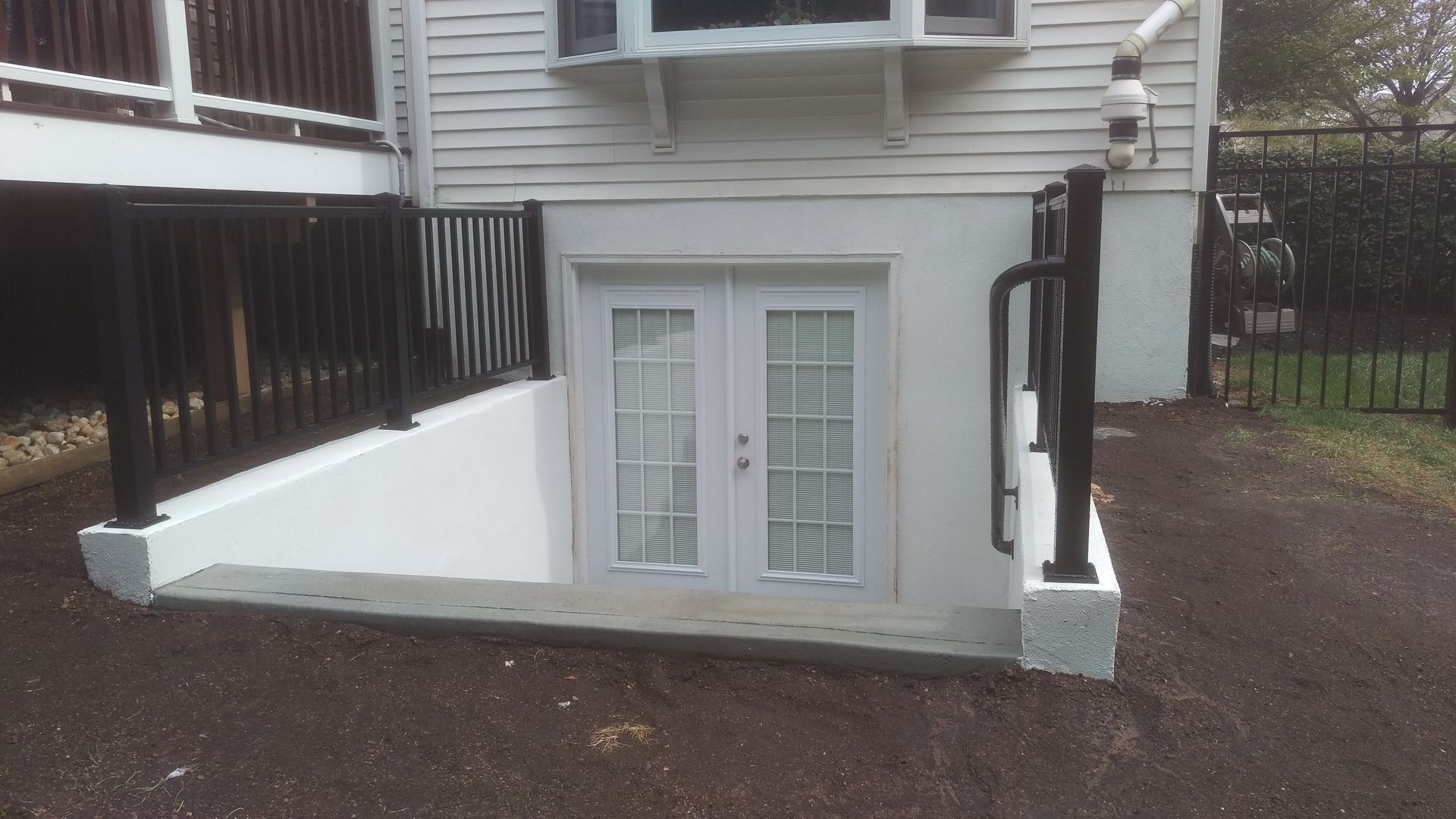 A white house with a staircase leading up to a basement.