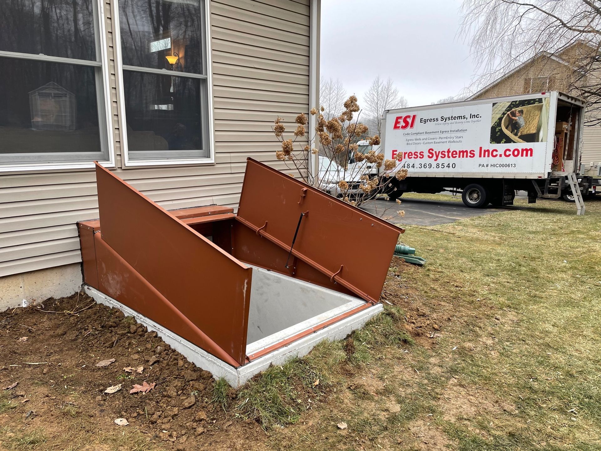 A man is standing in front of a house with a window and a fence.