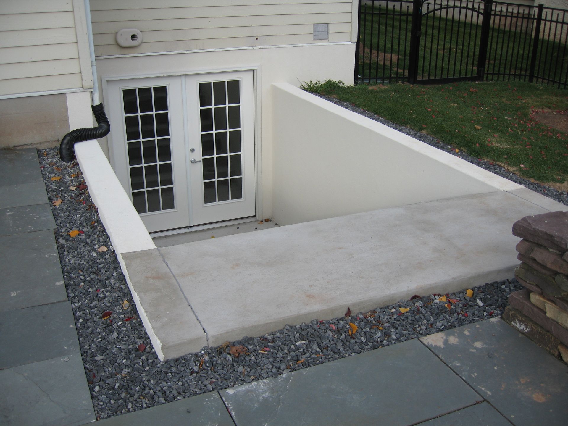 A concrete walkway leading to a basement door