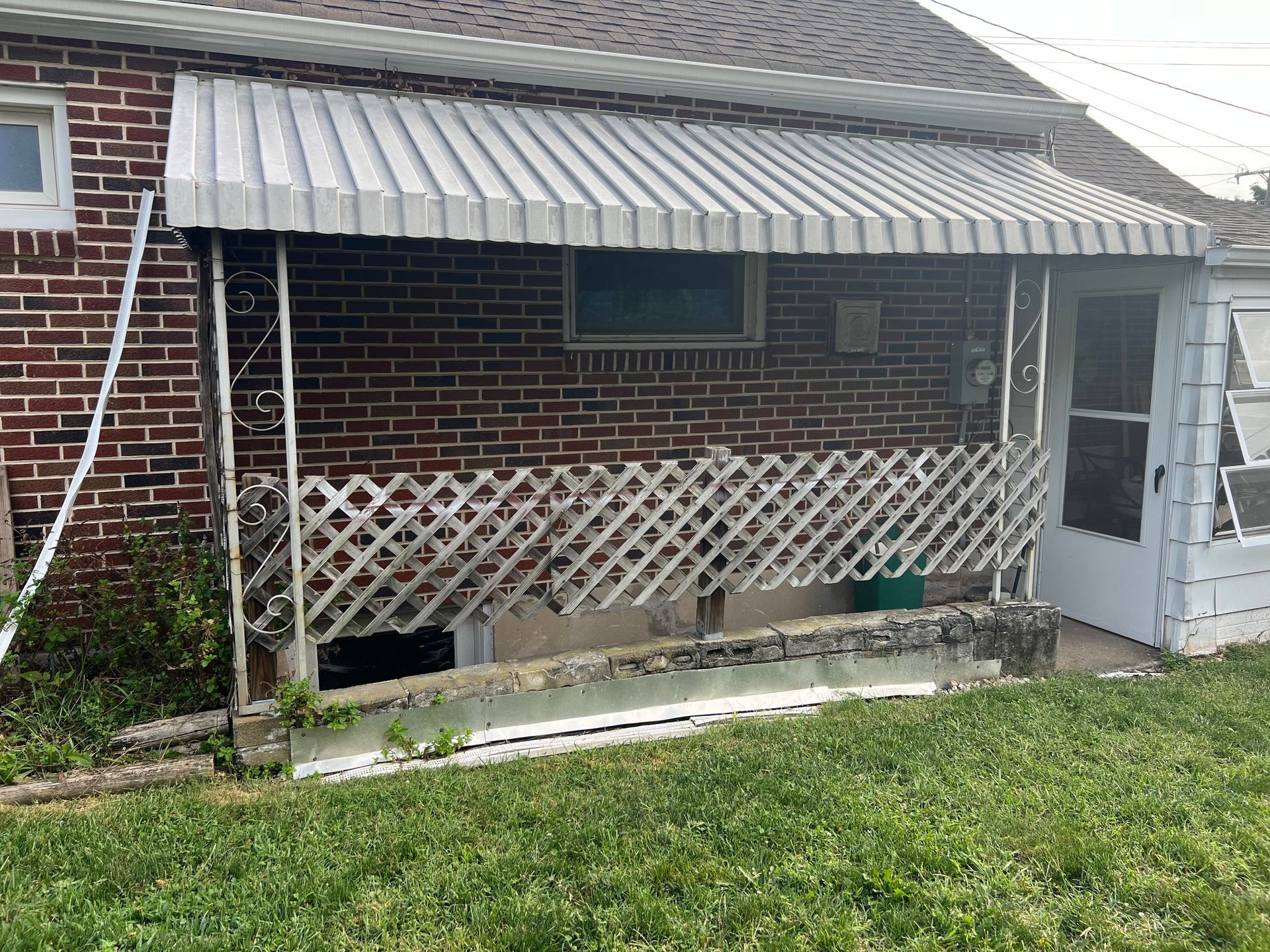 A brick house with a metal awning on the porch.