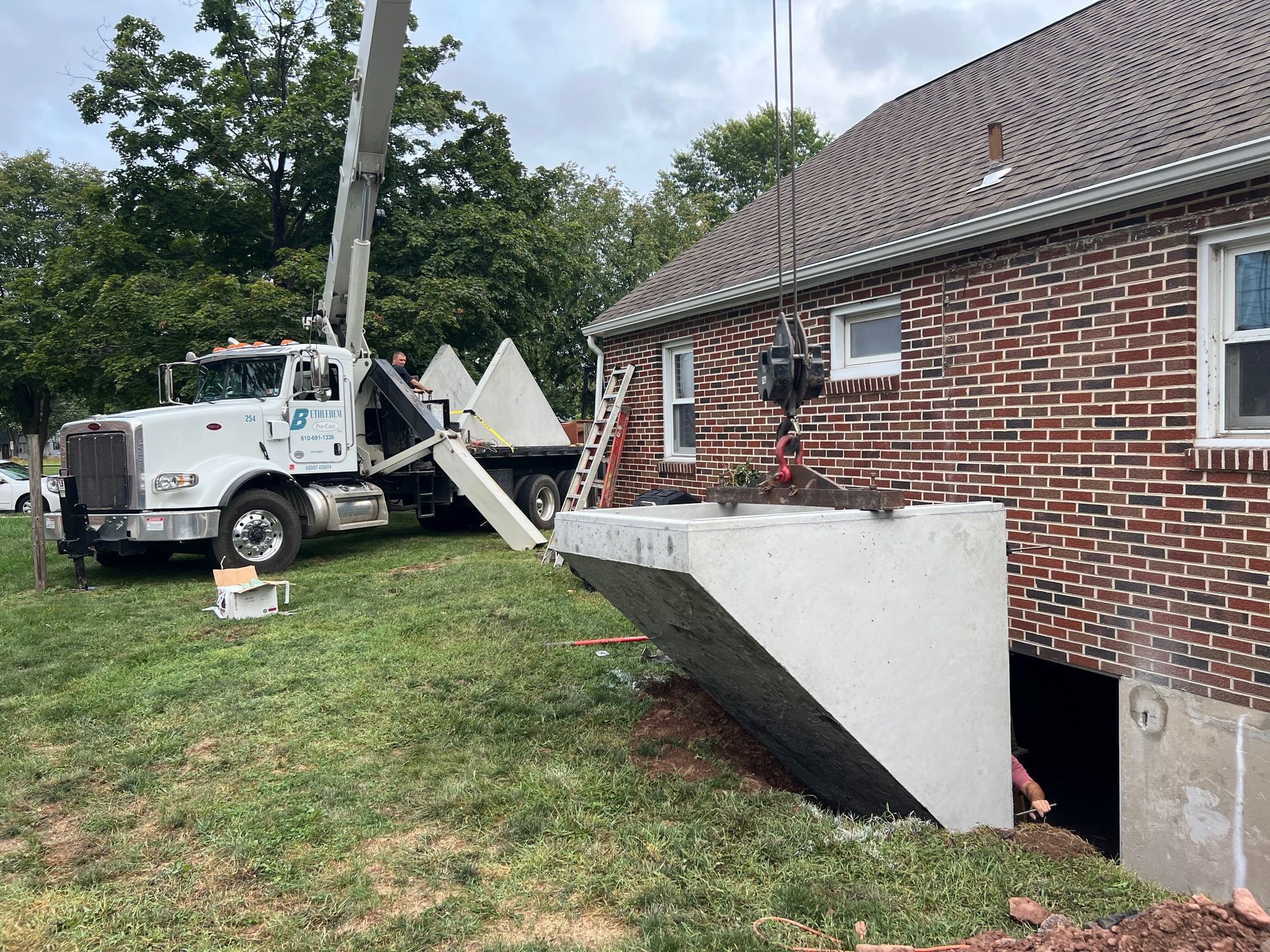 A white truck is parked in front of a brick house.