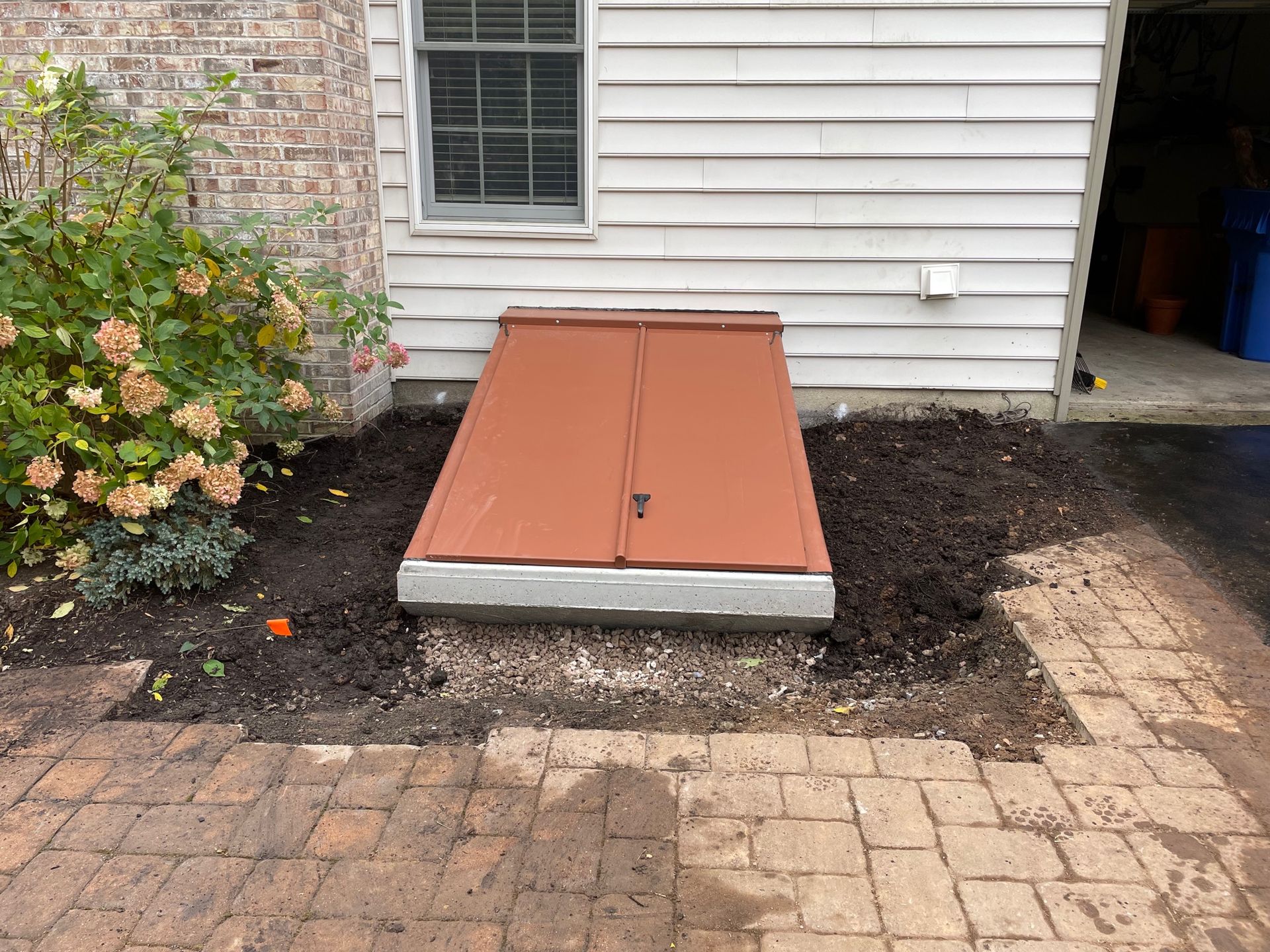 A red door is sitting in the dirt in front of a house.