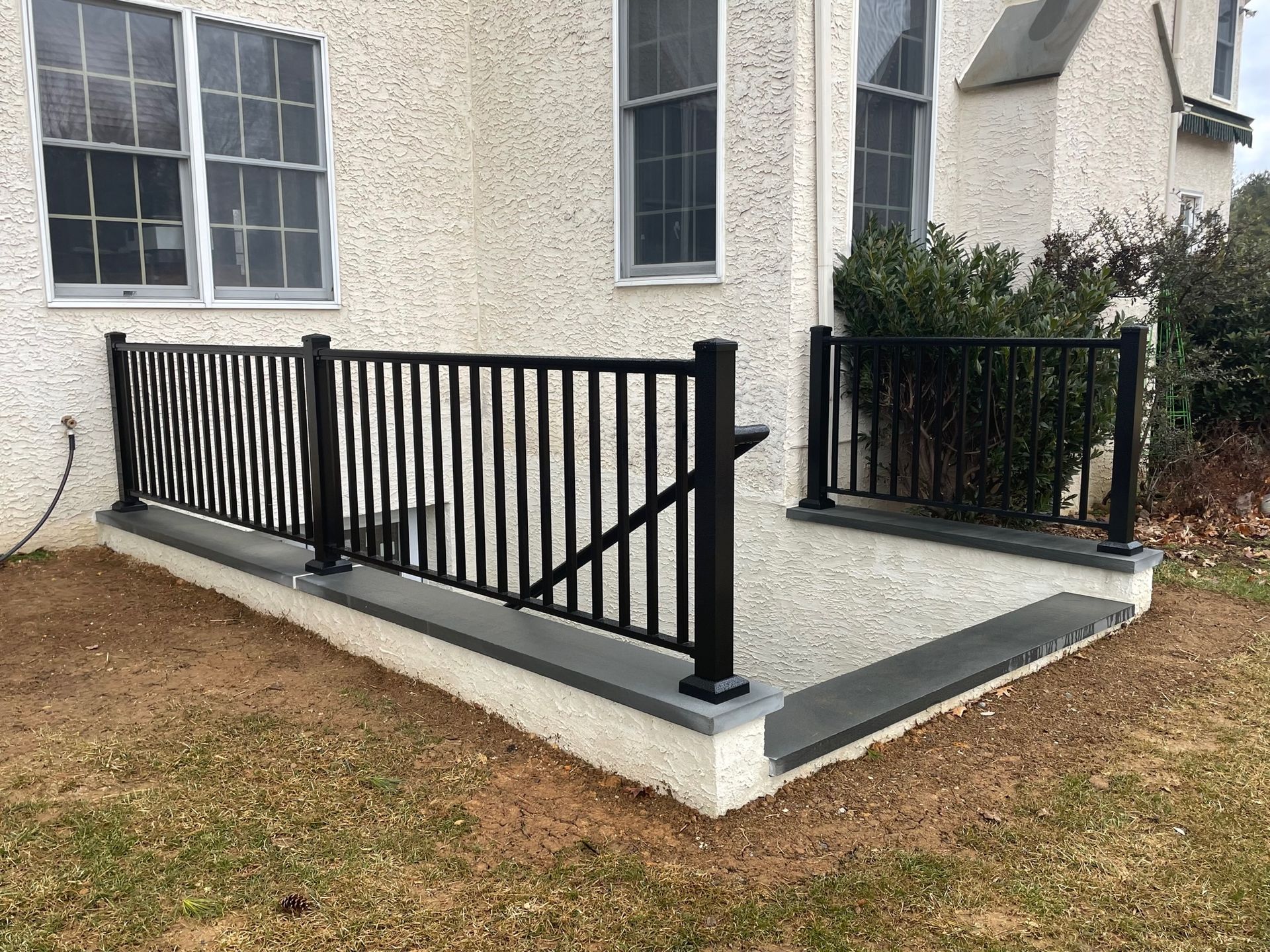 A white house with a black railing on the side of it.