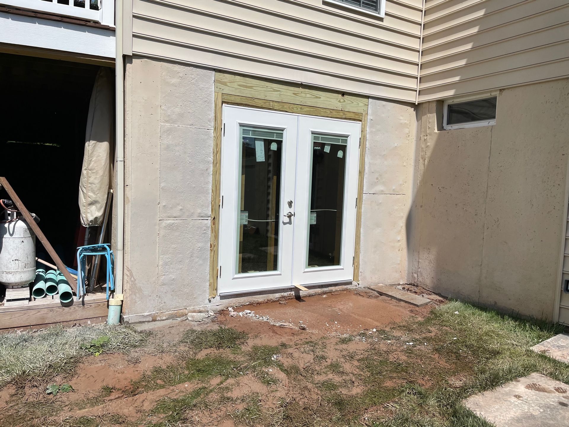 A white sliding glass door is being installed on the side of a house.