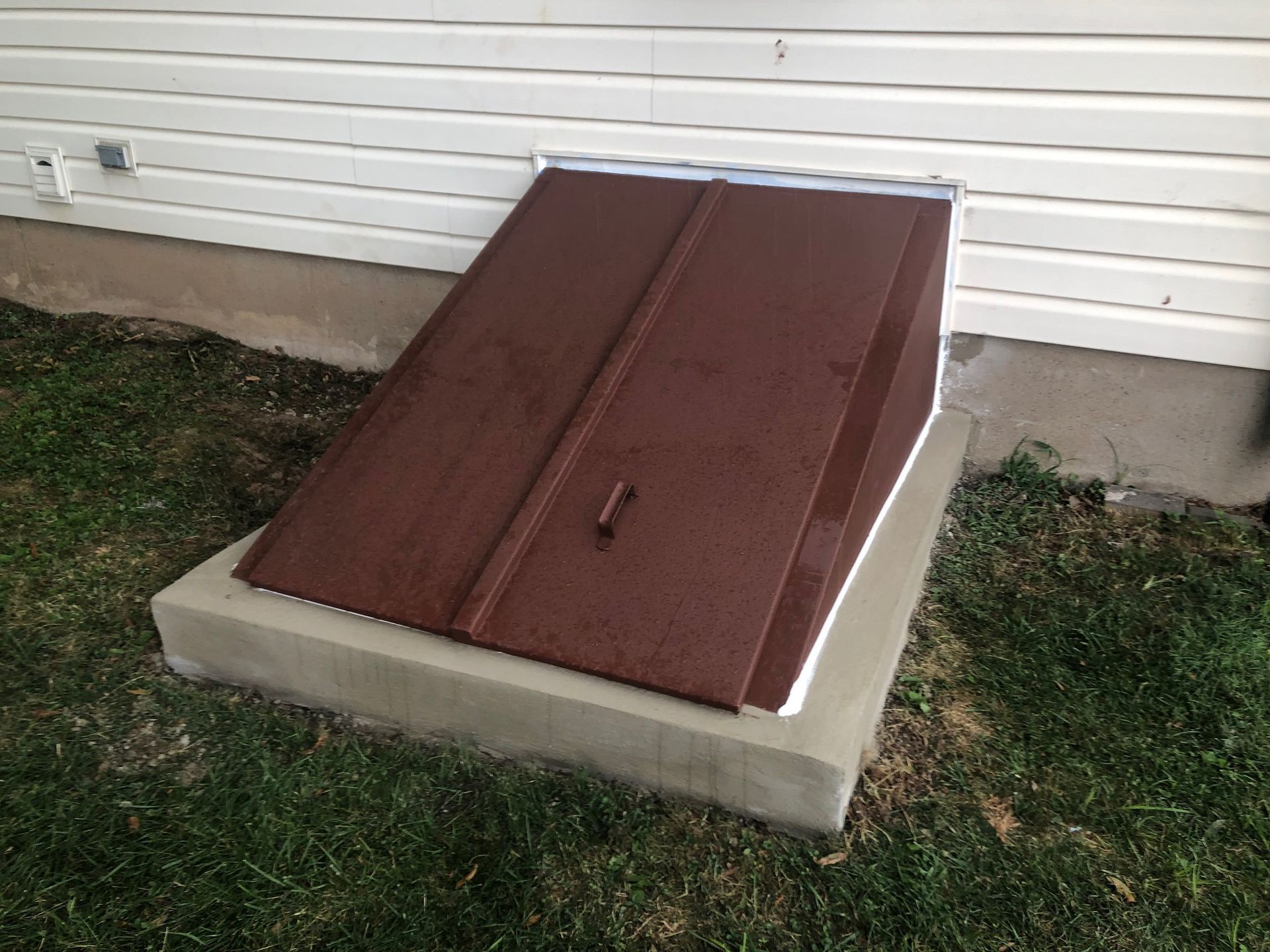 A large piece of wood is sitting in the grass in front of a house.