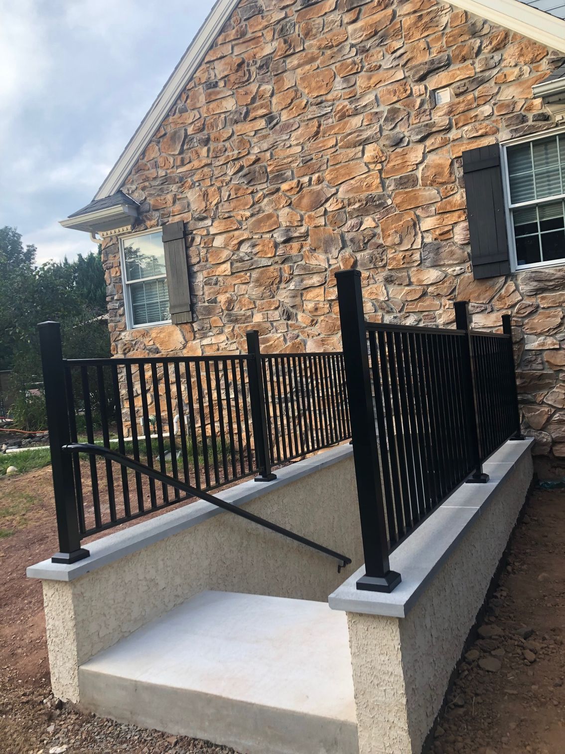 A stone house with a ramp and a wrought iron railing