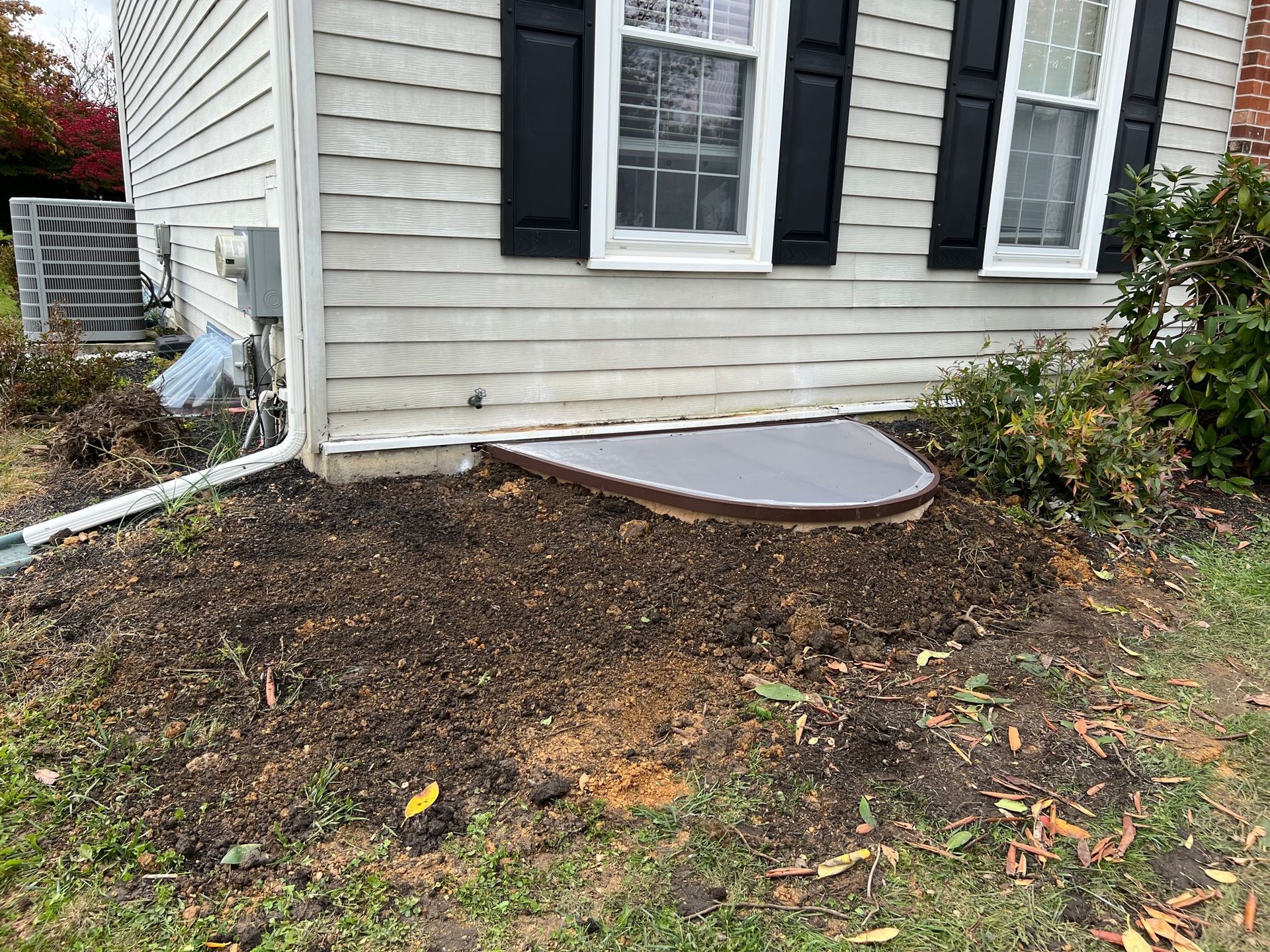 A white house with black shutters and a window that is covered in dirt.