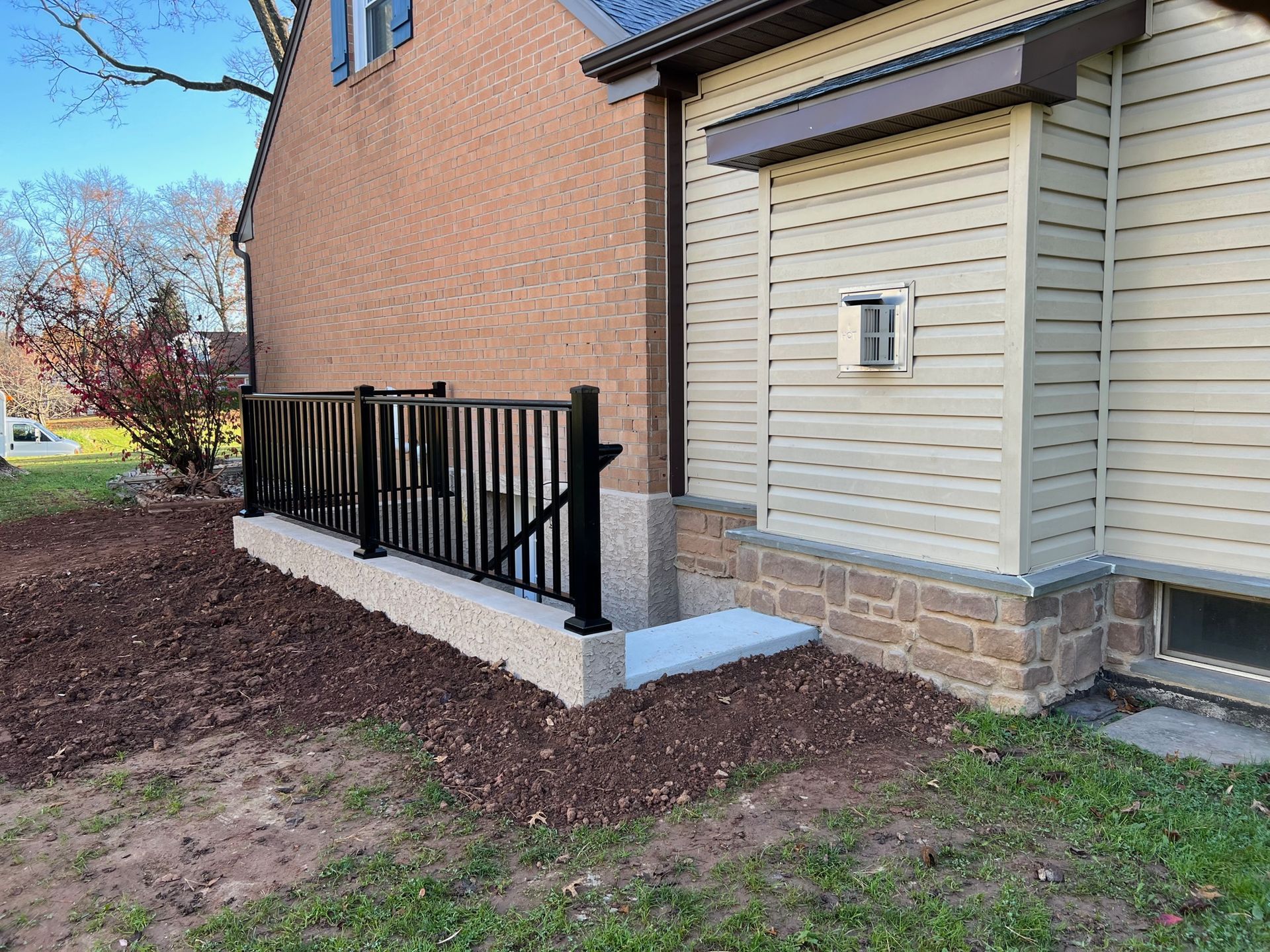 A house with a fence and stairs leading to the basement.