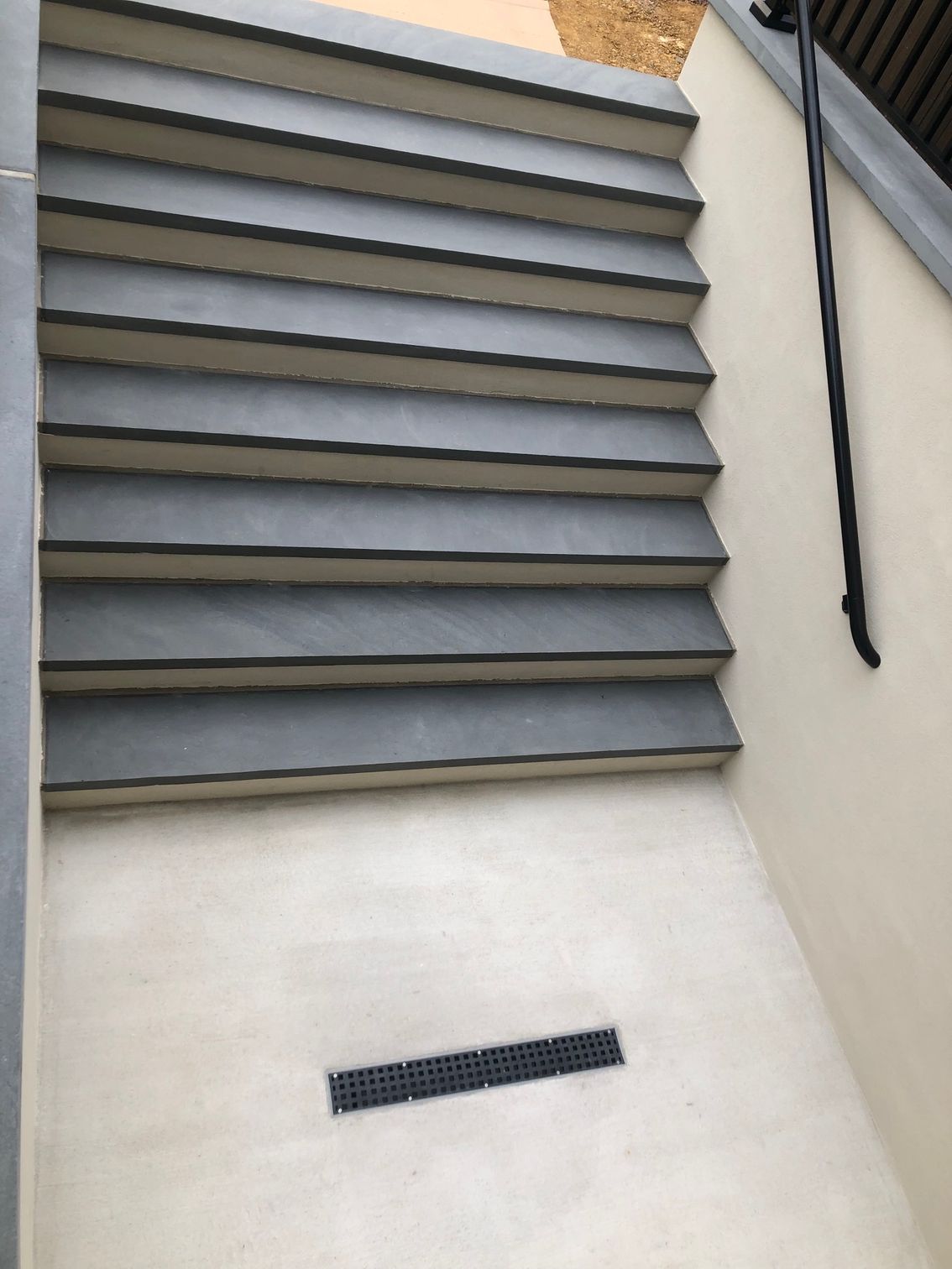 A set of stairs with a black railing on a white wall