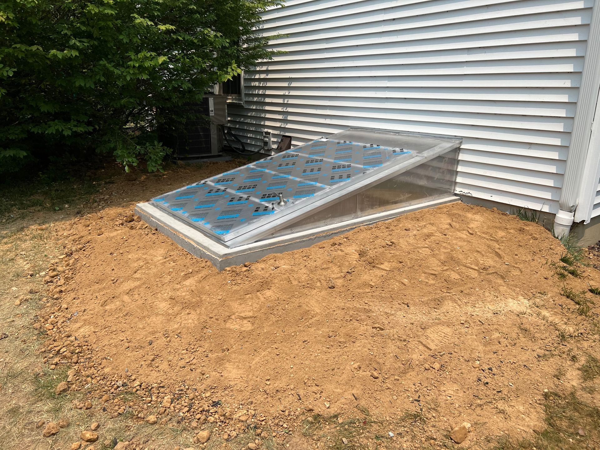 A window in the ground next to a white house.
