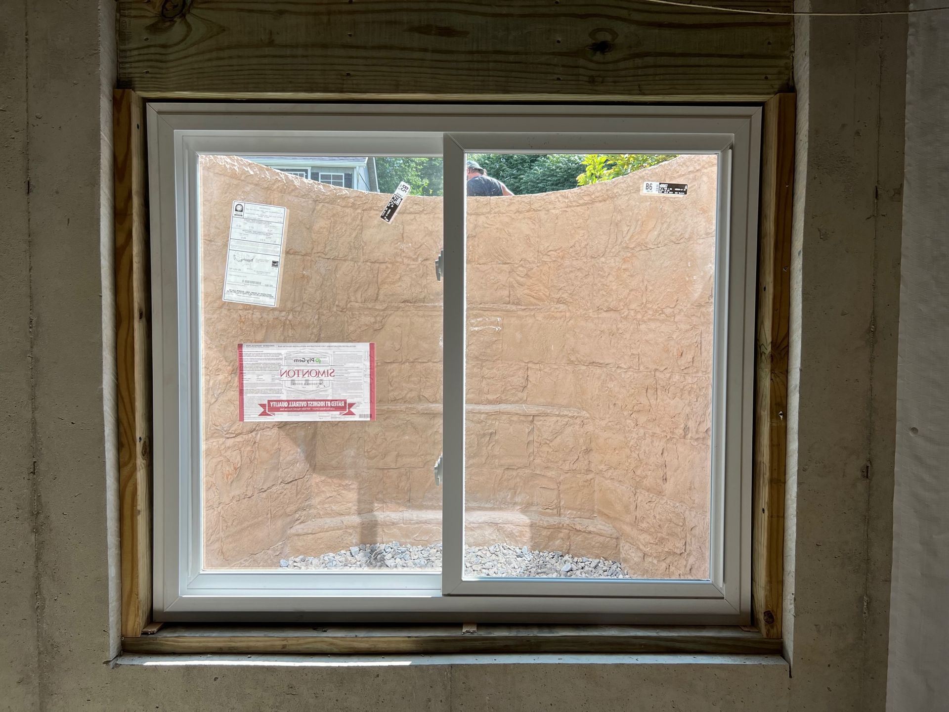 A window is being installed in a room with a wall behind it.
