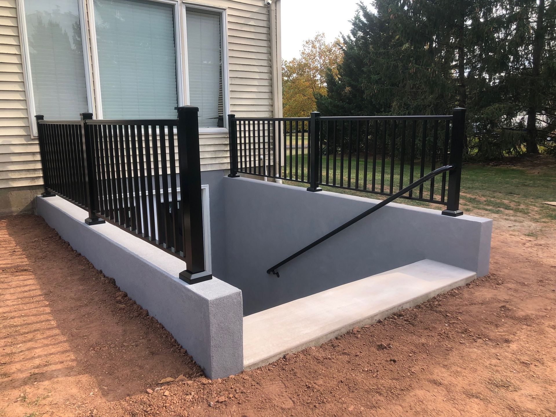 A staircase leading up to a basement with a black railing.