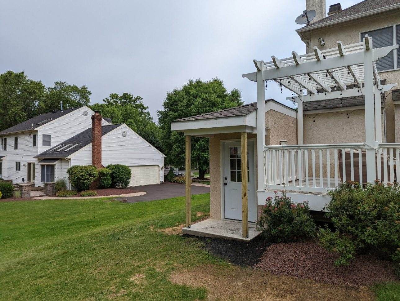 A house with a pergola and a deck in front of it.