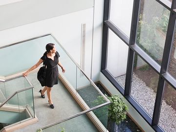Businesswoman with briefcase on stairs on office building - - Glass Company in Saint Petersburg, FL