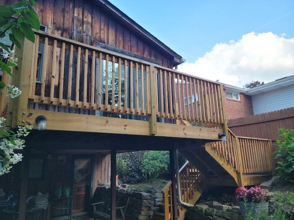 A wooden deck with stairs leading up to it is in front of a house.