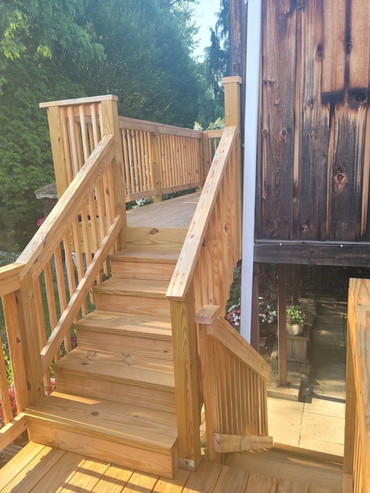 A wooden deck with stairs leading up to a wooden building.