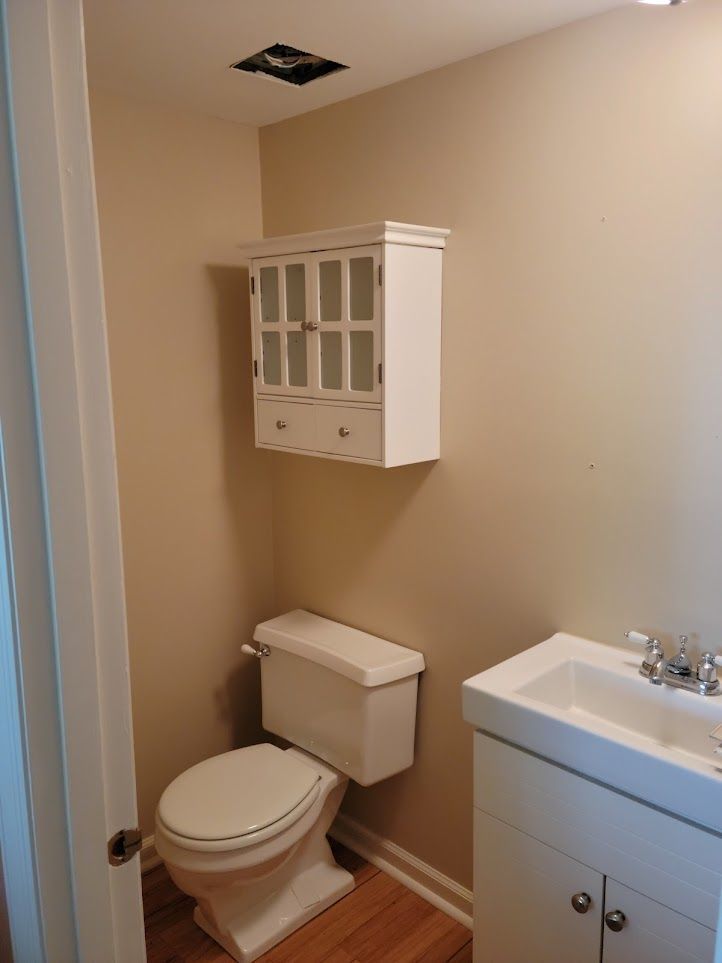 A bathroom with a toilet , sink and cabinet above it
