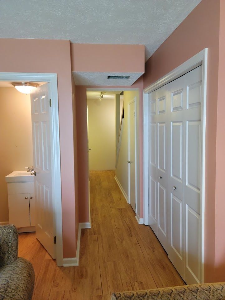 A hallway with pink walls and white doors