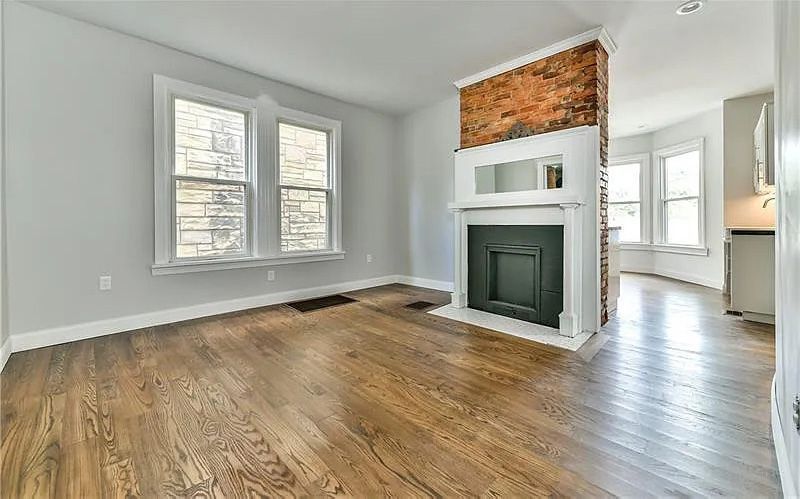 An empty living room with hardwood floors and a fireplace.