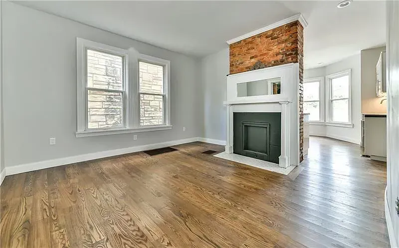 An empty bedroom with a ceiling fan and two windows.