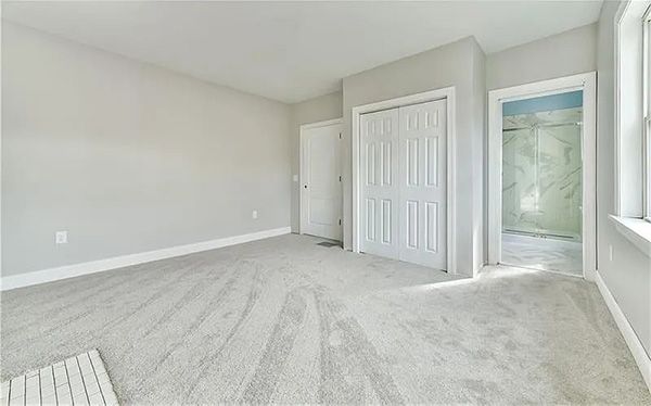 An empty bedroom with a closet and a window.