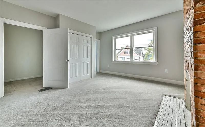 An empty living room with a fireplace and a large window.