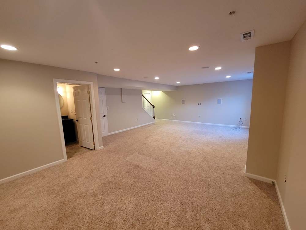 An empty basement with a staircase and a bathroom.