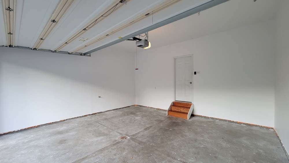 An empty garage with a door and stairs.