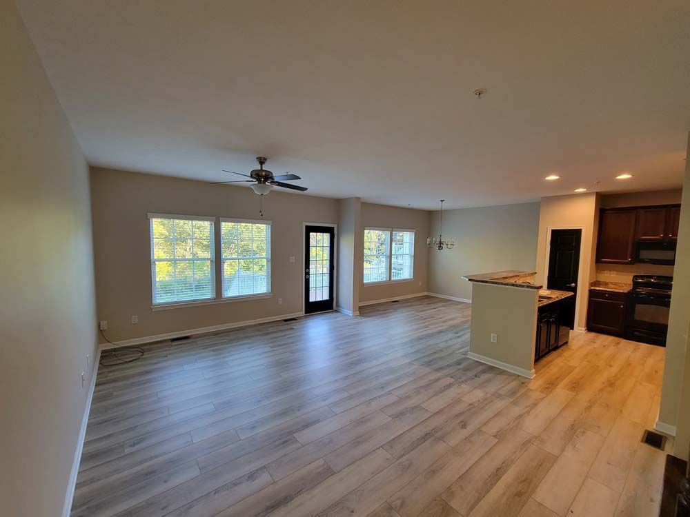 An empty living room with hardwood floors and a ceiling fan.