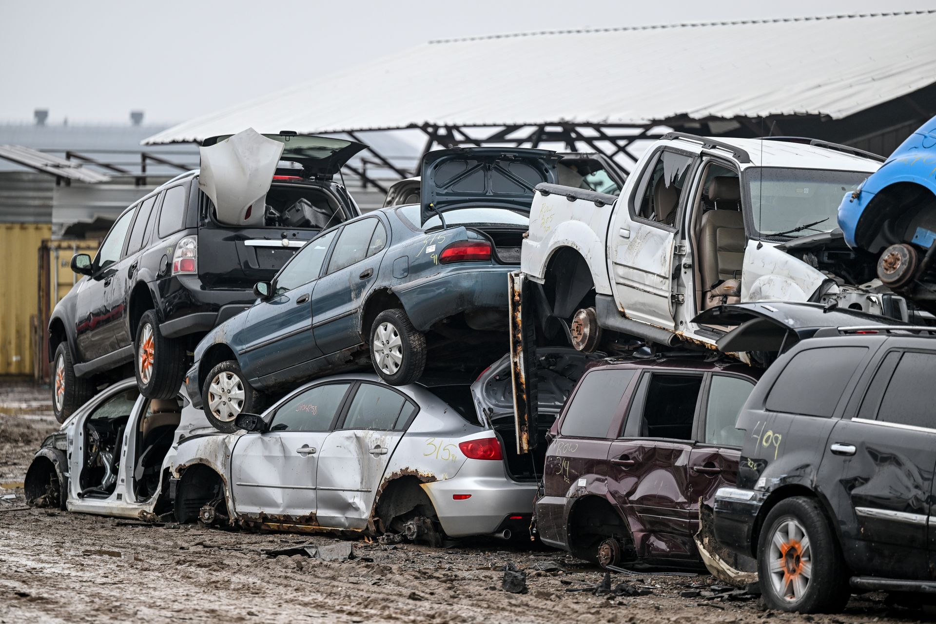 A bunch of cars are stacked on top of each other in a junkyard.