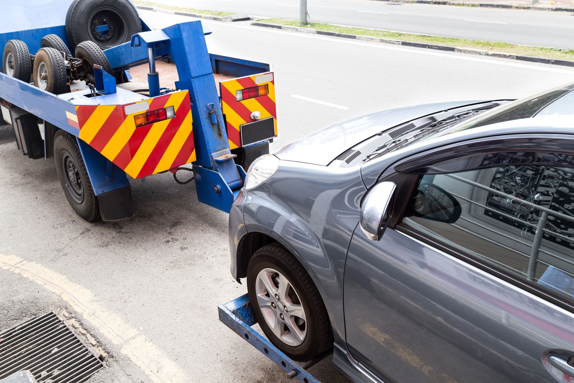 A car is being towed by a tow truck on the side of the road.