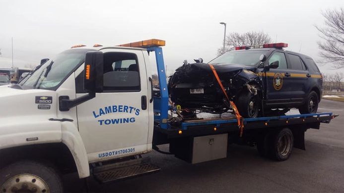 A police car is being towed by a lambert 's towing truck