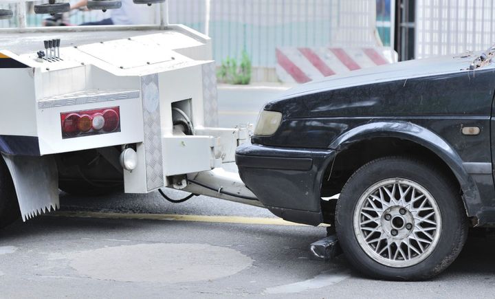 A black car is being towed by a tow truck