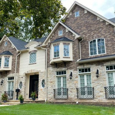 A large brick house with a lot of windows and a large lawn in front of it.