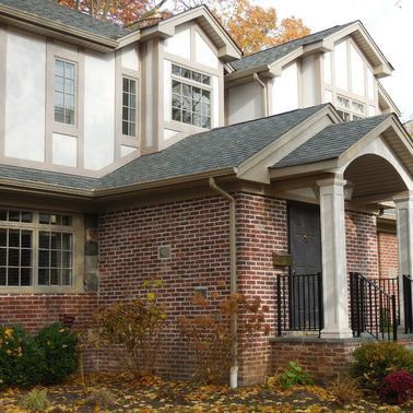 A brick house with a porch and a gray roof