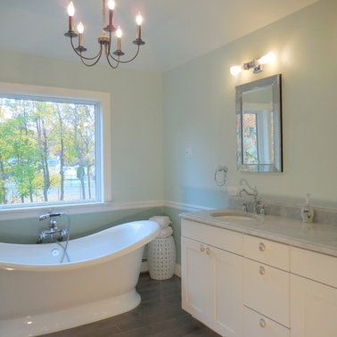 A bathroom with a tub , sink , mirror and window