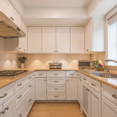 A kitchen with white cabinets , wooden counter tops , a sink , and a stove.