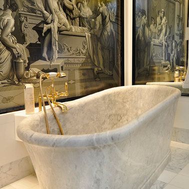 A bathtub in a bathroom with two paintings on the wall behind it.