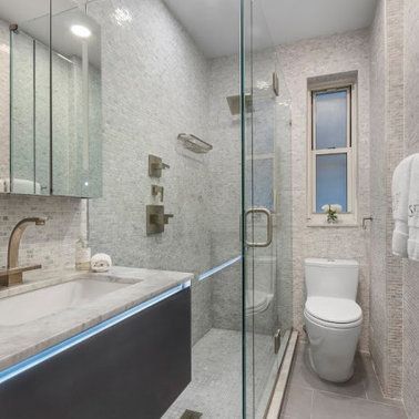 A bathroom with a toilet , sink , shower and window.