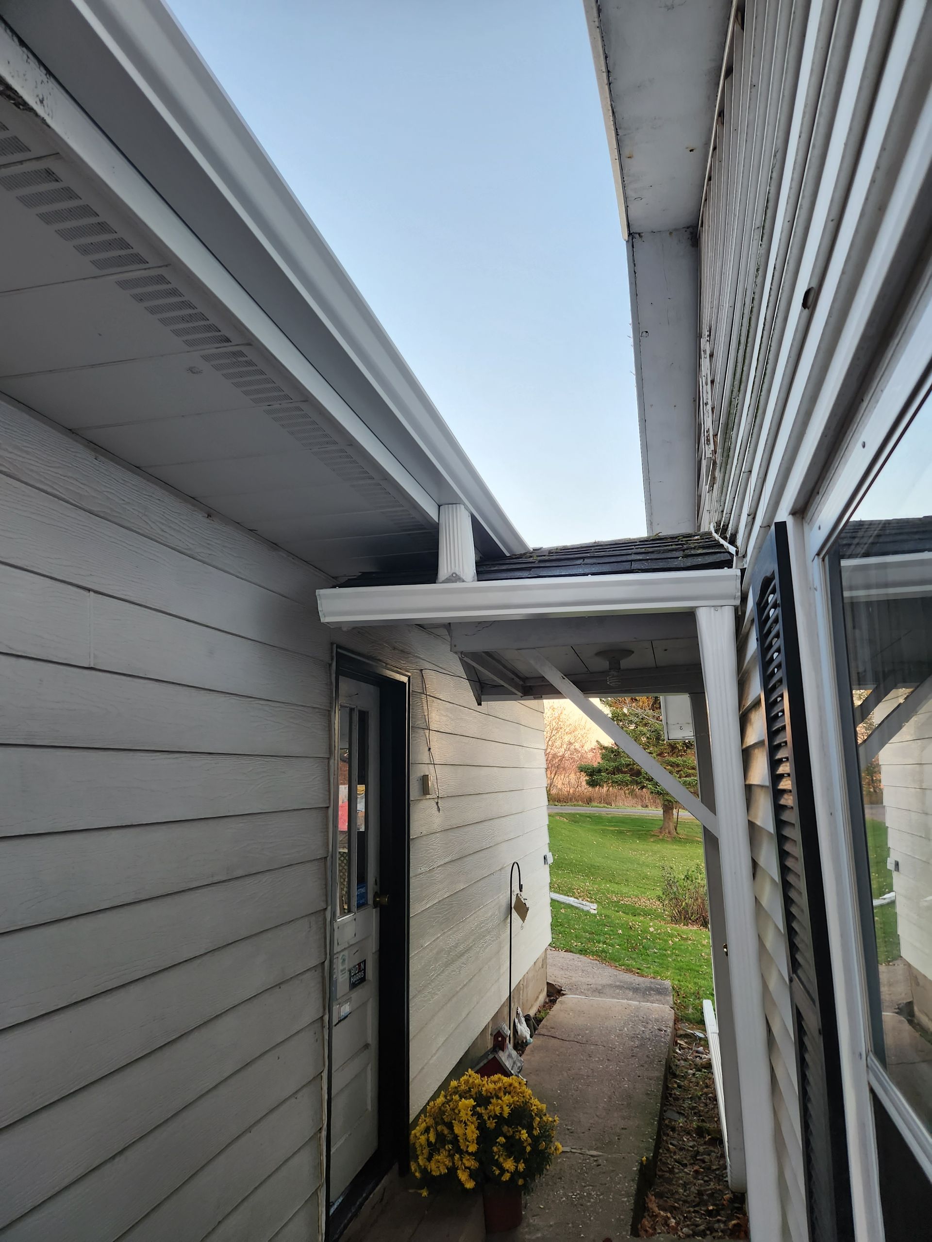 A white house with a porch and a gutter on the side