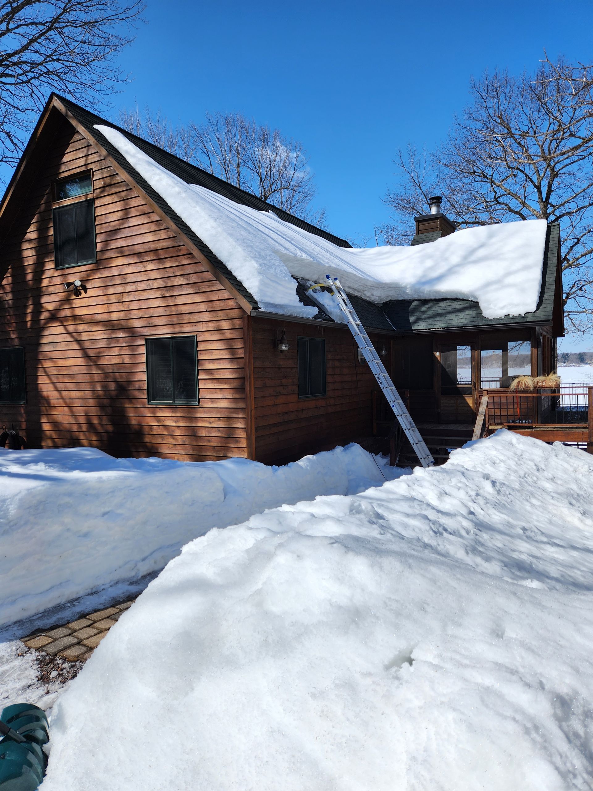 A brick house with snow on the roof is surrounded by snow