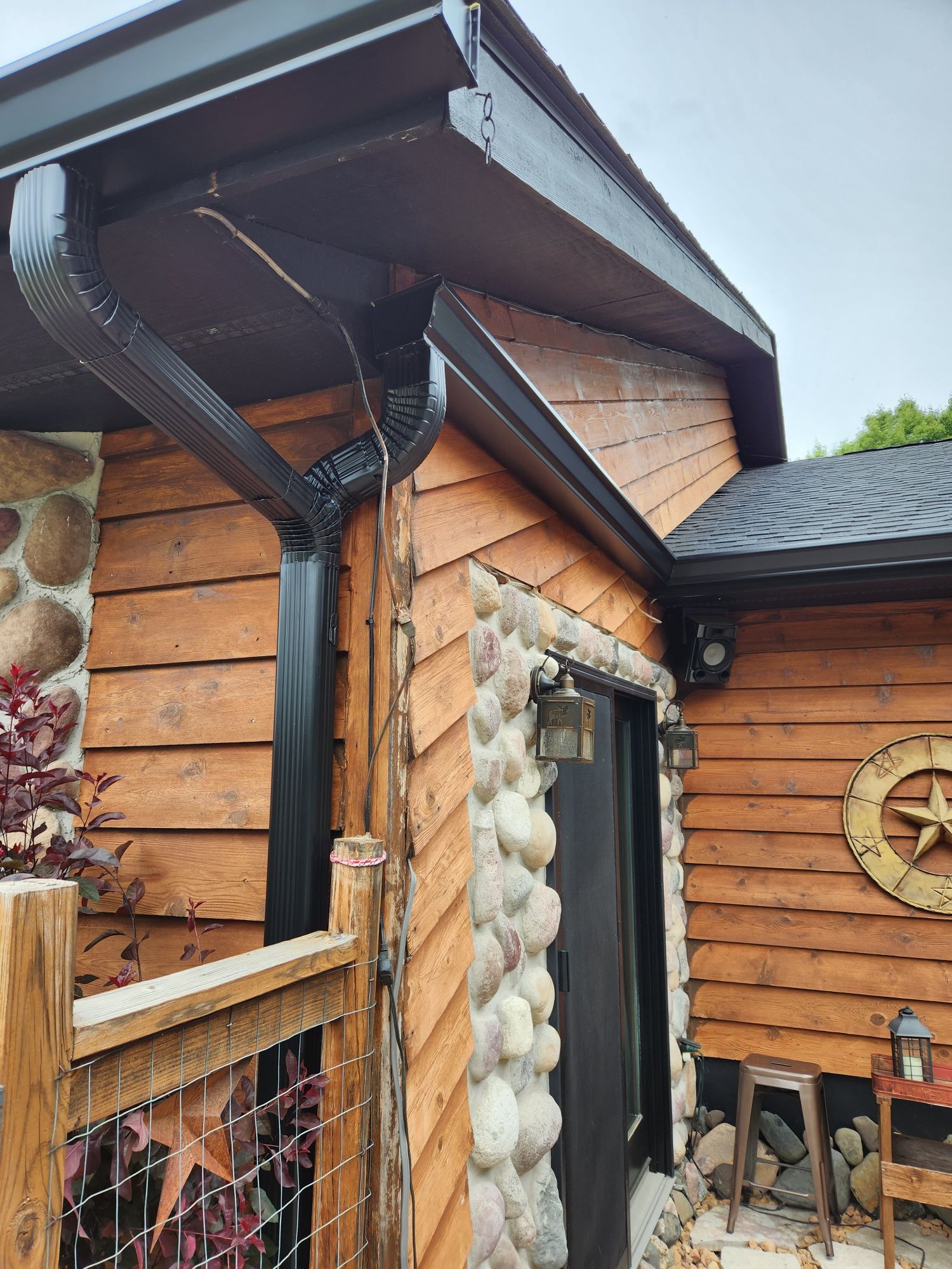 A wooden house with a black gutter on the side of it.